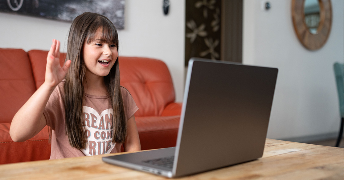 Florida Virtual Public Schools Open for 2026-27 Enrollment A girl sits in front of a laptop smiling while conversing with someone on the computer for her Florida Virtual School class.