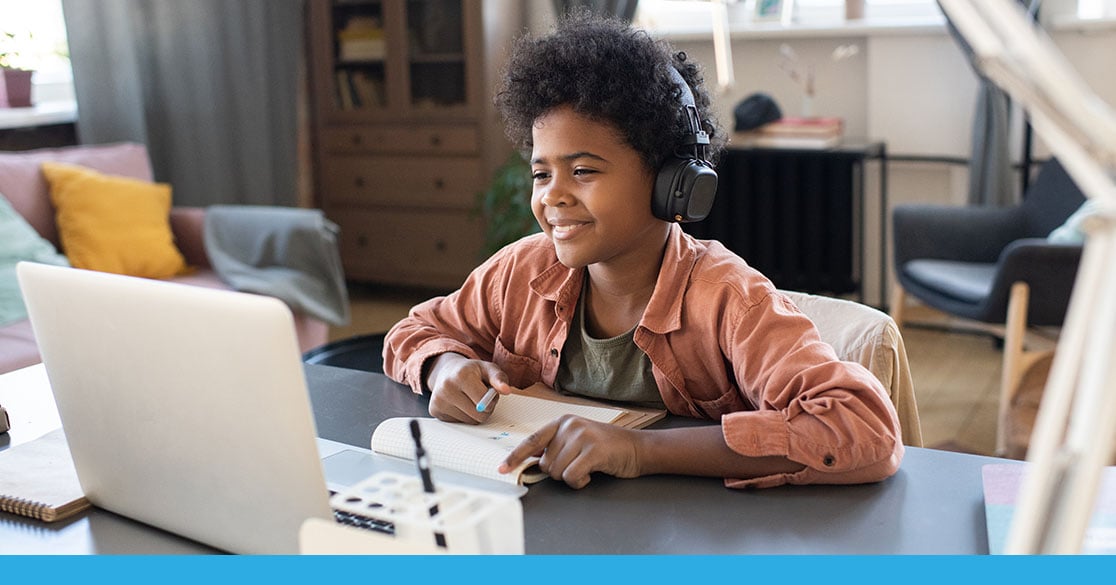 FLVS Has An Online Learning Option for Every Student Student participating in Florida Virtual School online learning, using a laptop and headphones while taking notes at a home study space.