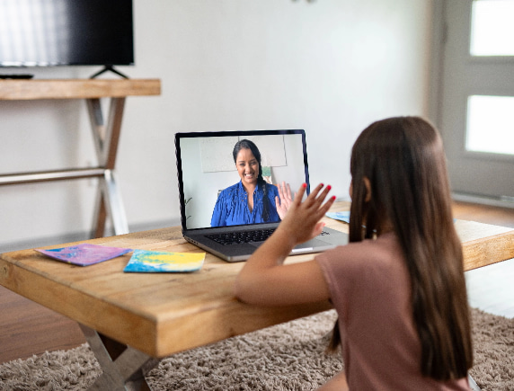 Student waving to teacher on laptop screen